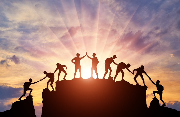 Silhouette of climbers who climbed to the top of the mountain thanks to mutual assistance and teamwork. 